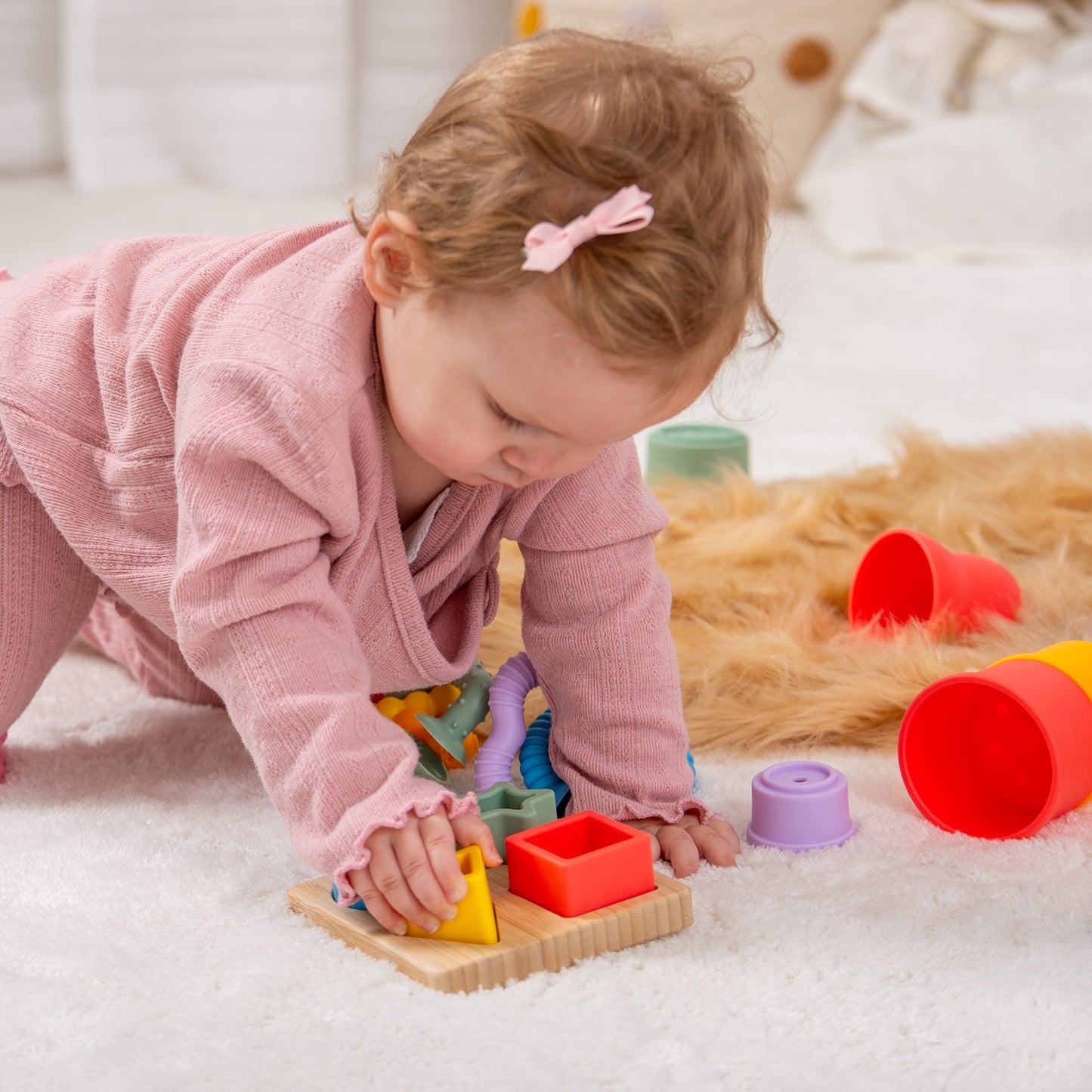 Baby playing with colorful shape sorter toy on soft rug, early learning activity for toddlers