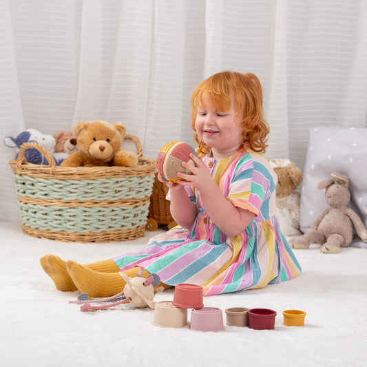 Child playing with colorful stacking toys and soft teddy bears in a cozy playroom setting