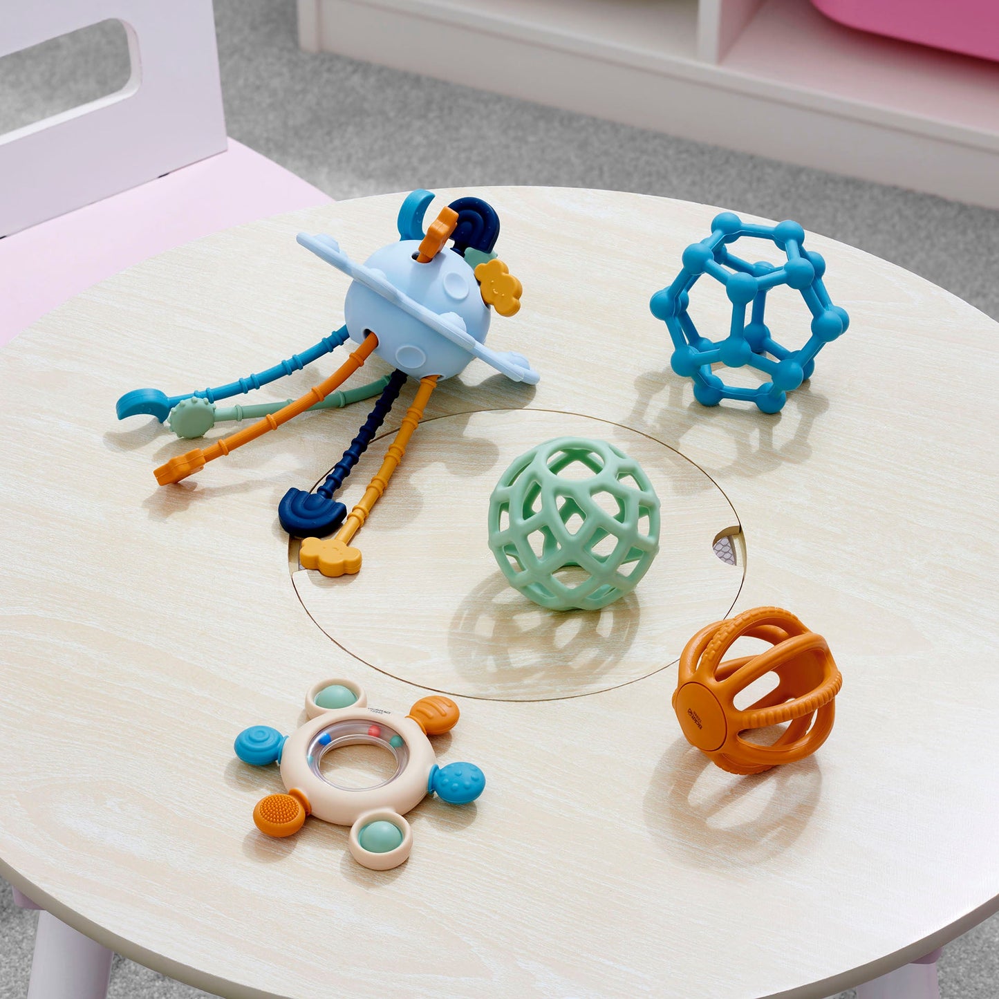 Colorful baby sensory toys including teething balls and activity rattle on wooden table
