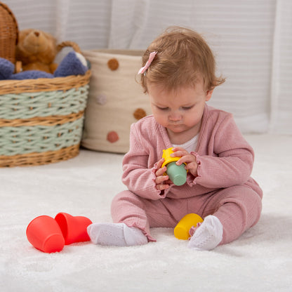Baby playing with colorful stacking cups on soft rug, ideal for toddler development and playtime fun
