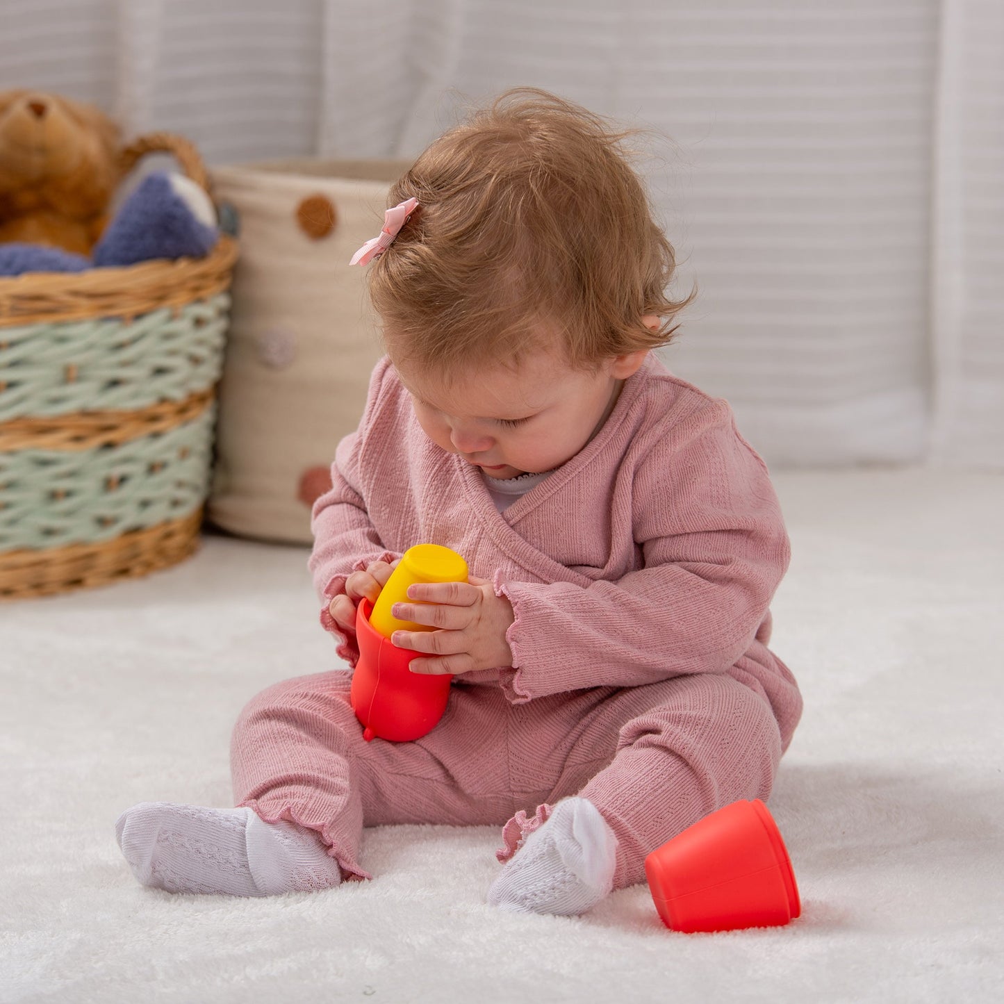 Baby playing with colorful stacking cups on soft rug, developmental toy for toddlers