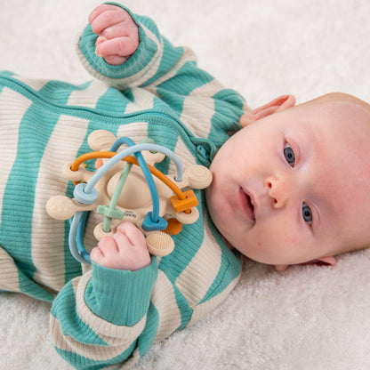 Baby playing with colorful sensory teether toy on soft blanket