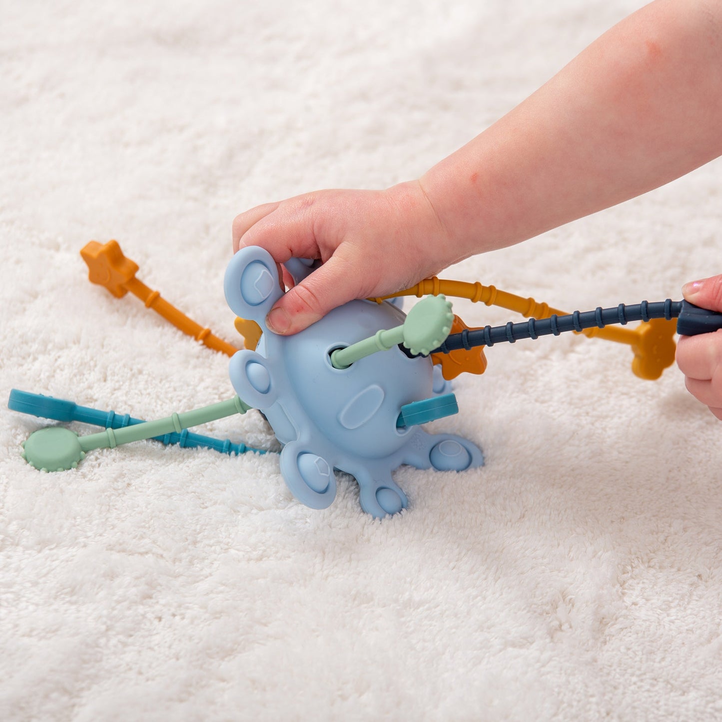 Child playing with colorful octopus-shaped sensory toy on soft rug