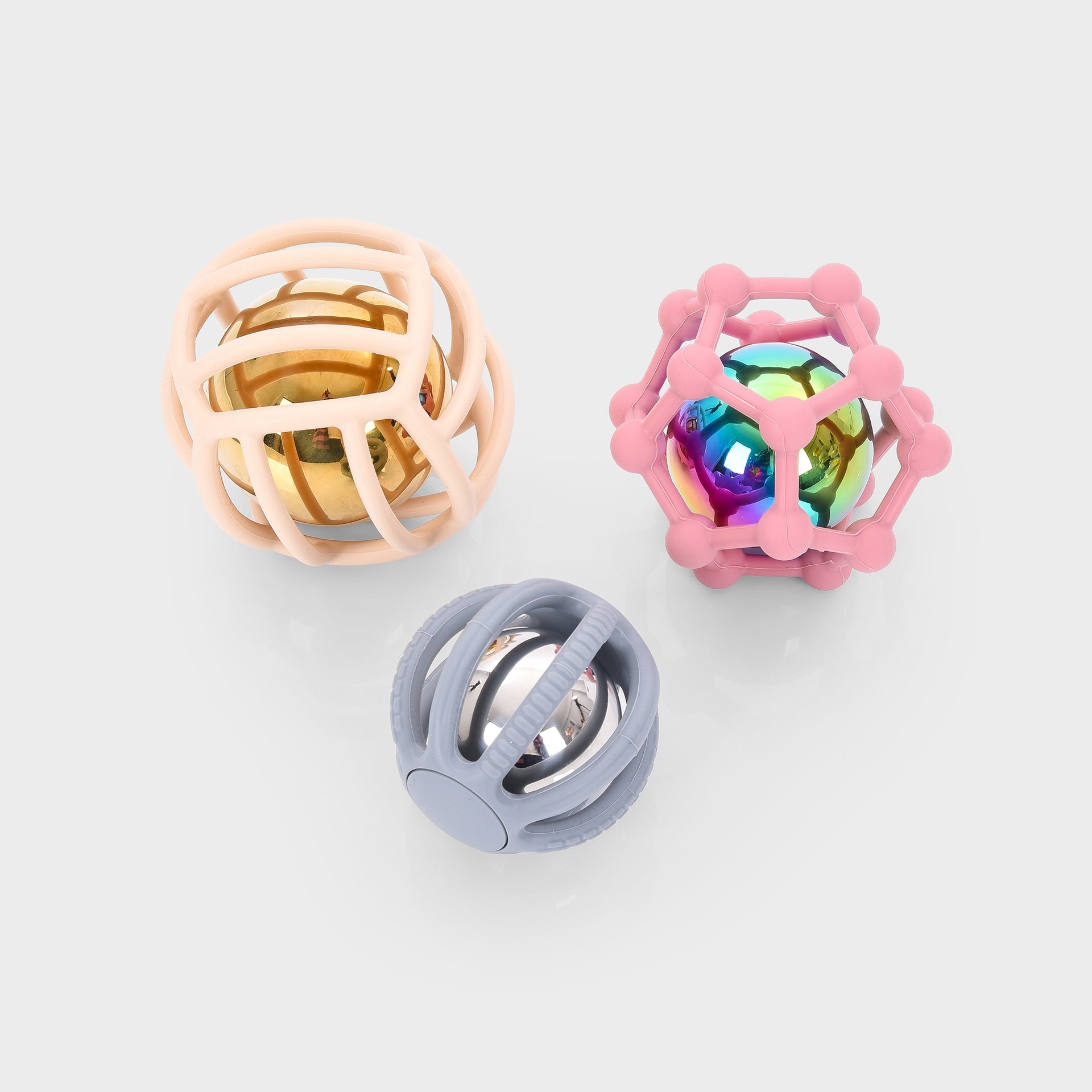 Three sensory baby rattle balls with colorful metallic cores and soft silicone cages for teething and play