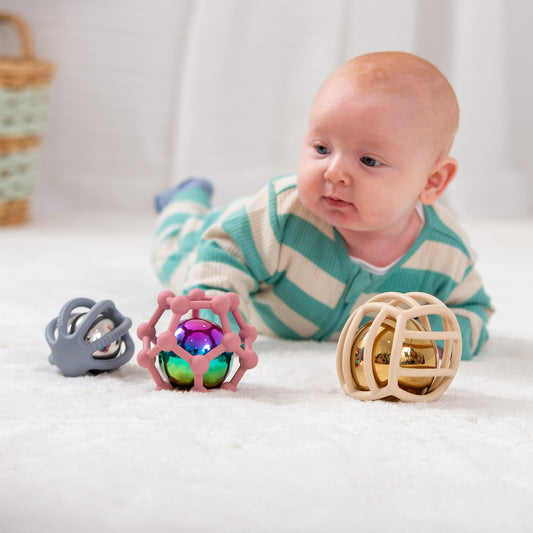 Baby playing with colorful sensory balls on soft rug, developmental toys for infants