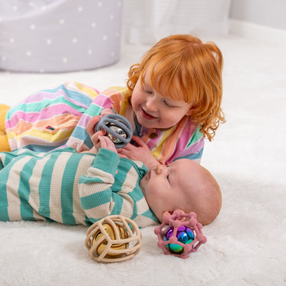 Toddler and baby playing with sensory rattle toys on soft rug, colorful developmental play