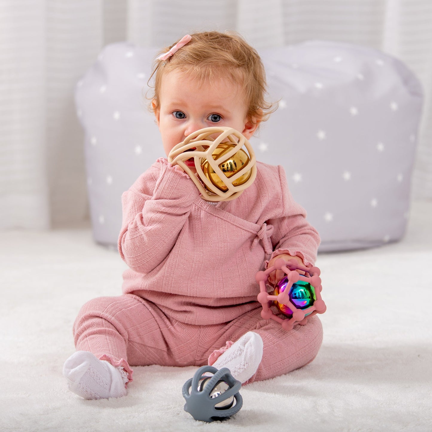 Baby playing with colorful sensory rattle toys, ideal for infant development and playtime fun.