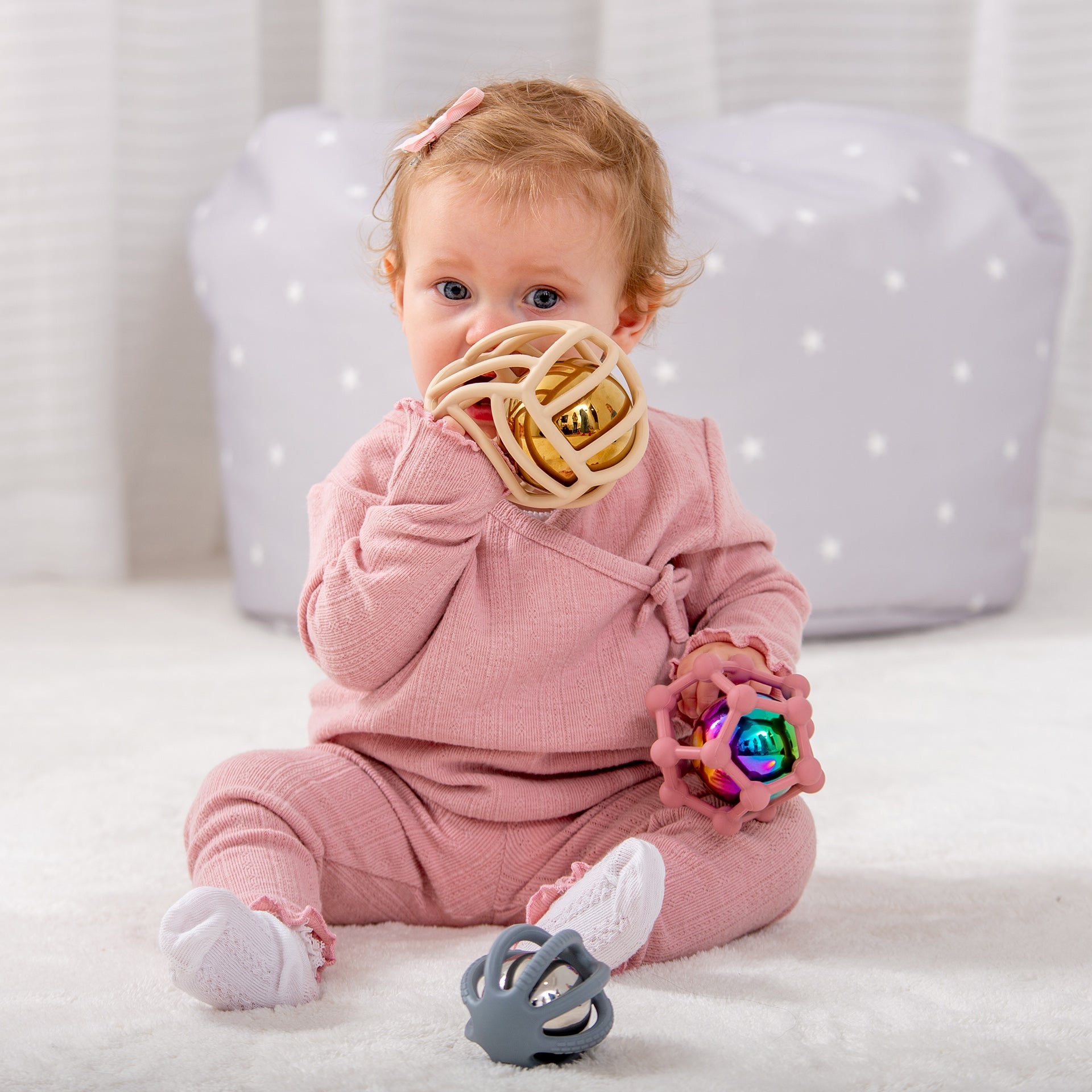 Baby playing with colorful sensory rattle toys, ideal for infant development and playtime fun.