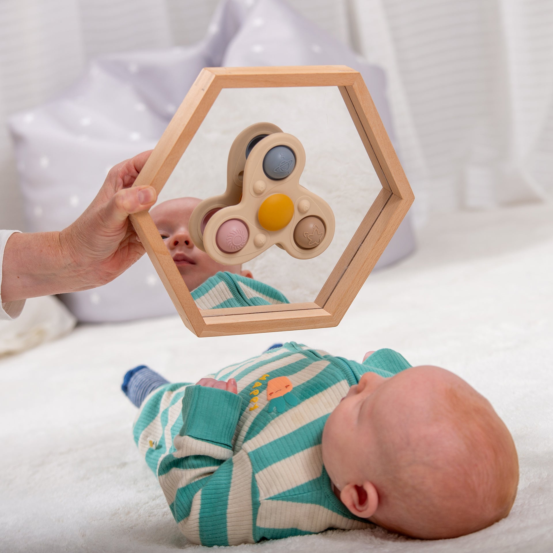 Baby playing with wooden hexagon mirror and sensory toy