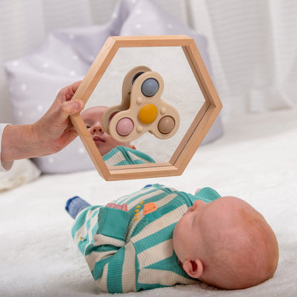 Baby playing with wooden hexagon mirror and sensory toy