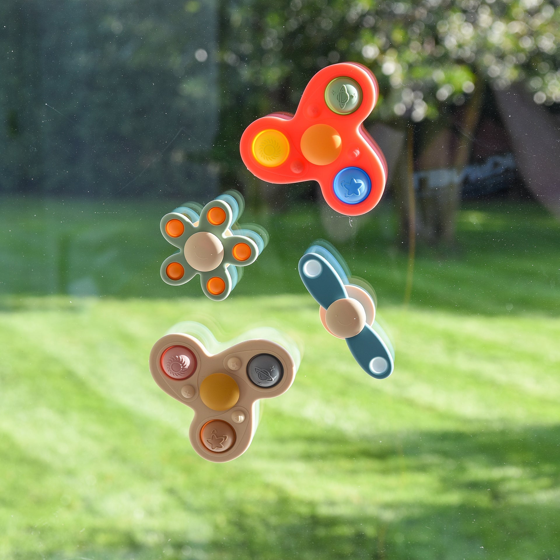 Colorful fidget spinners with pop-it bubbles on window, outdoor garden view background