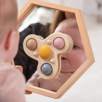 Baby playing with wooden hexagon mirror and sensory activity toy featuring colorful buttons and textures for tactile exploration