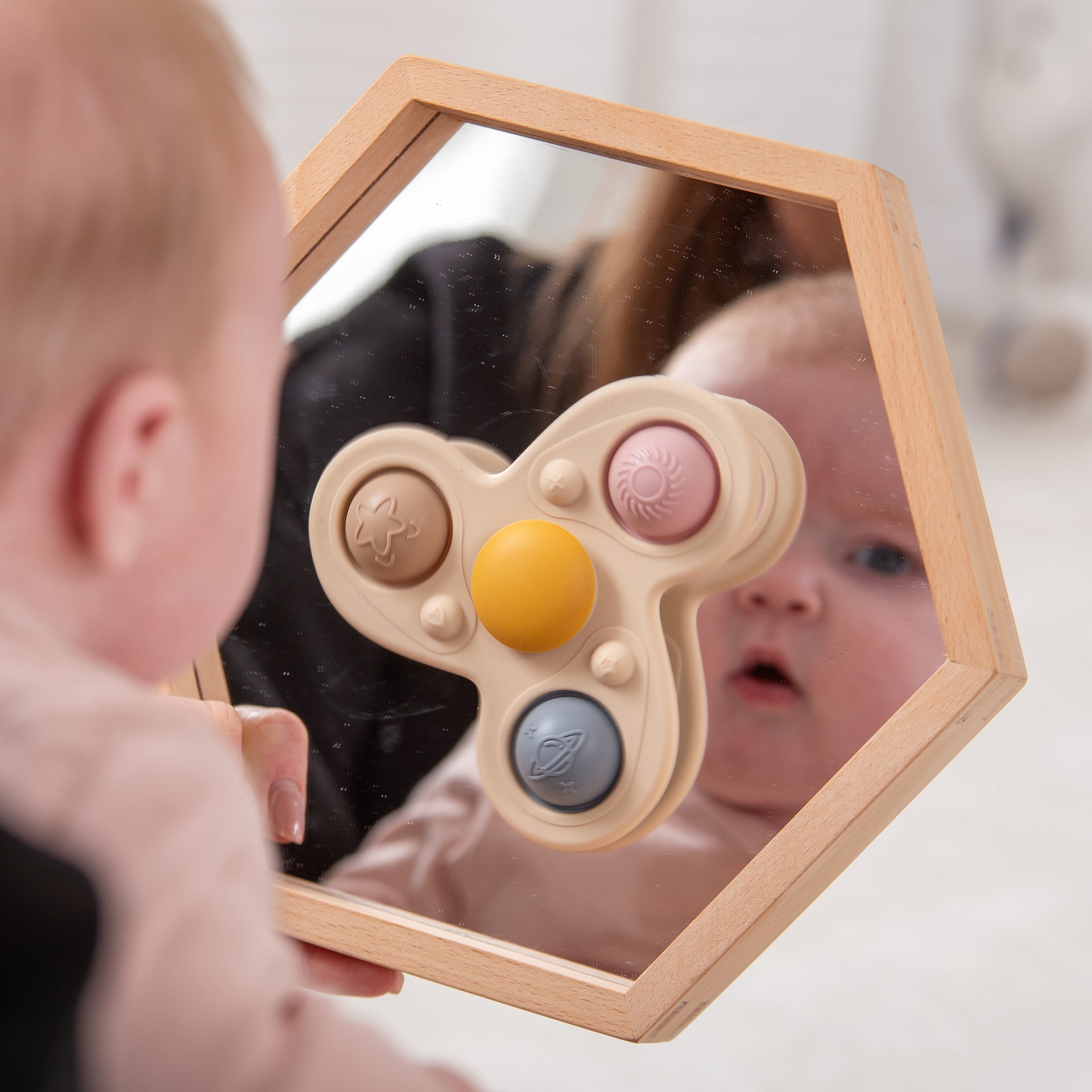 Baby exploring wooden mirror with colorful sensory buttons for early learning and play