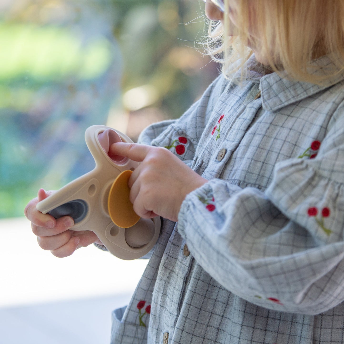 Child playing with sensory fidget toy, featuring colorful buttons and soft textures for tactile play.