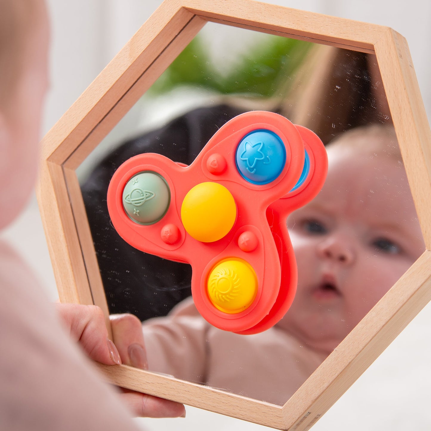 Baby looking at colorful space-themed fidget toy in wooden mirror, sensory play for infants