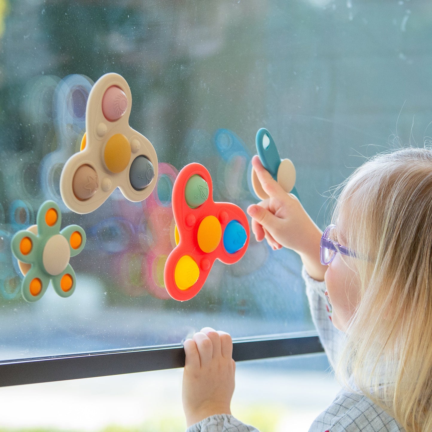 Child playing with colorful window cling toys, sensory fidget poppers for kids