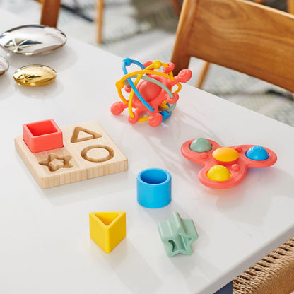 Colorful kids' shape sorter toys and sensory fidget spinner on white table