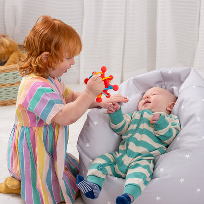 Child playing with baby using colorful sensory toy on star-patterned cushion