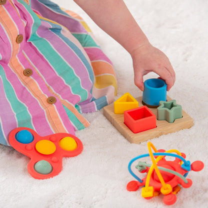Child playing with colorful shape sorter and sensory toys on soft rug