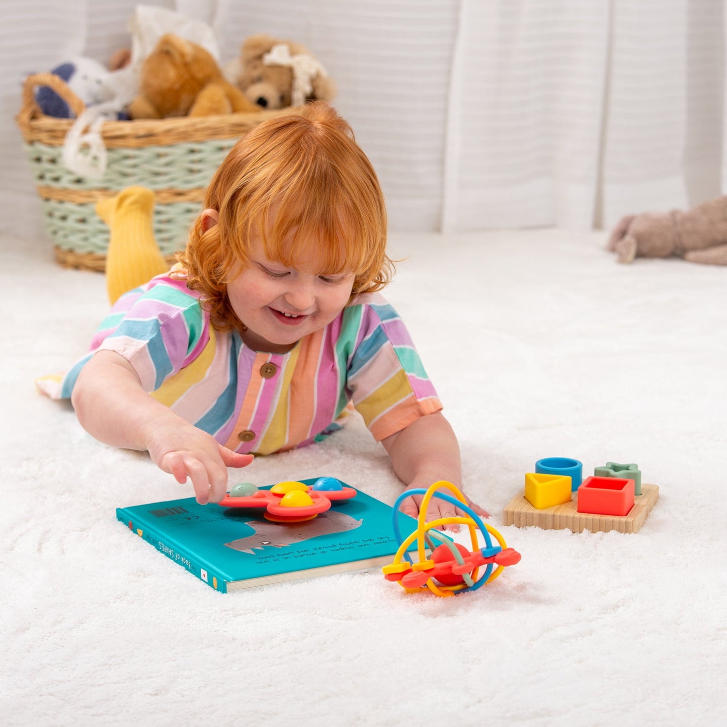 Child playing with colorful shape sorting toys and activity book on soft carpet