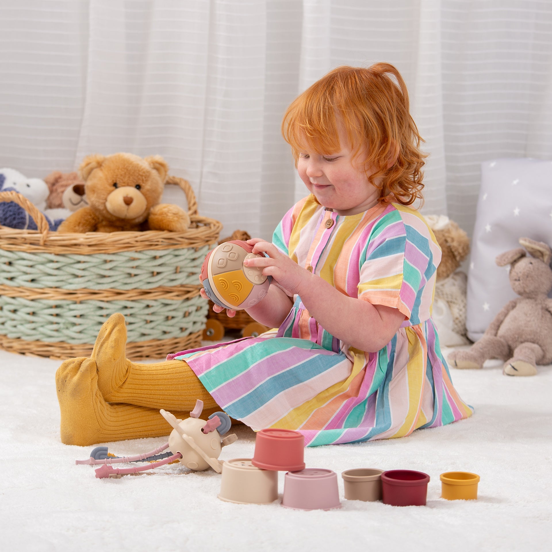 Child playing with colorful sensory toys and stacking cups on soft carpet