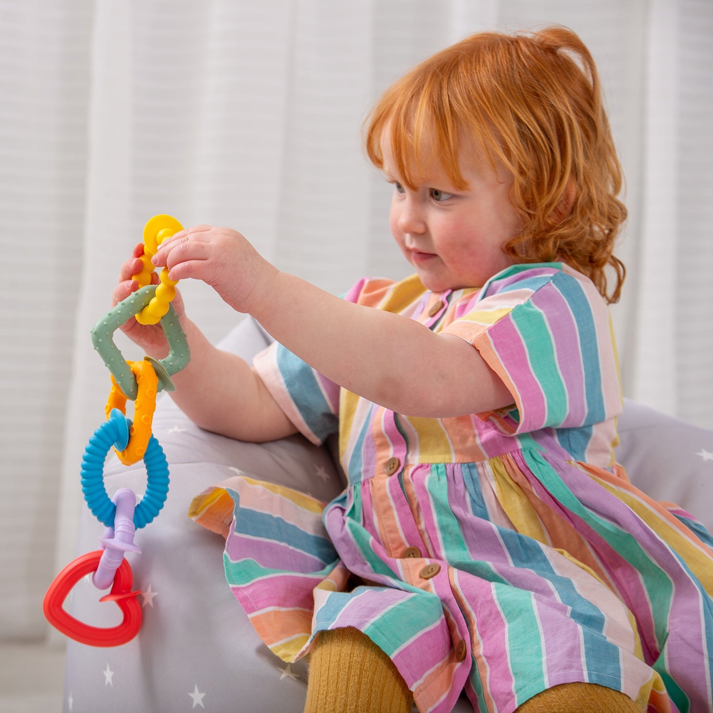 Toddler playing with colorful baby teething rings and sensory toy set