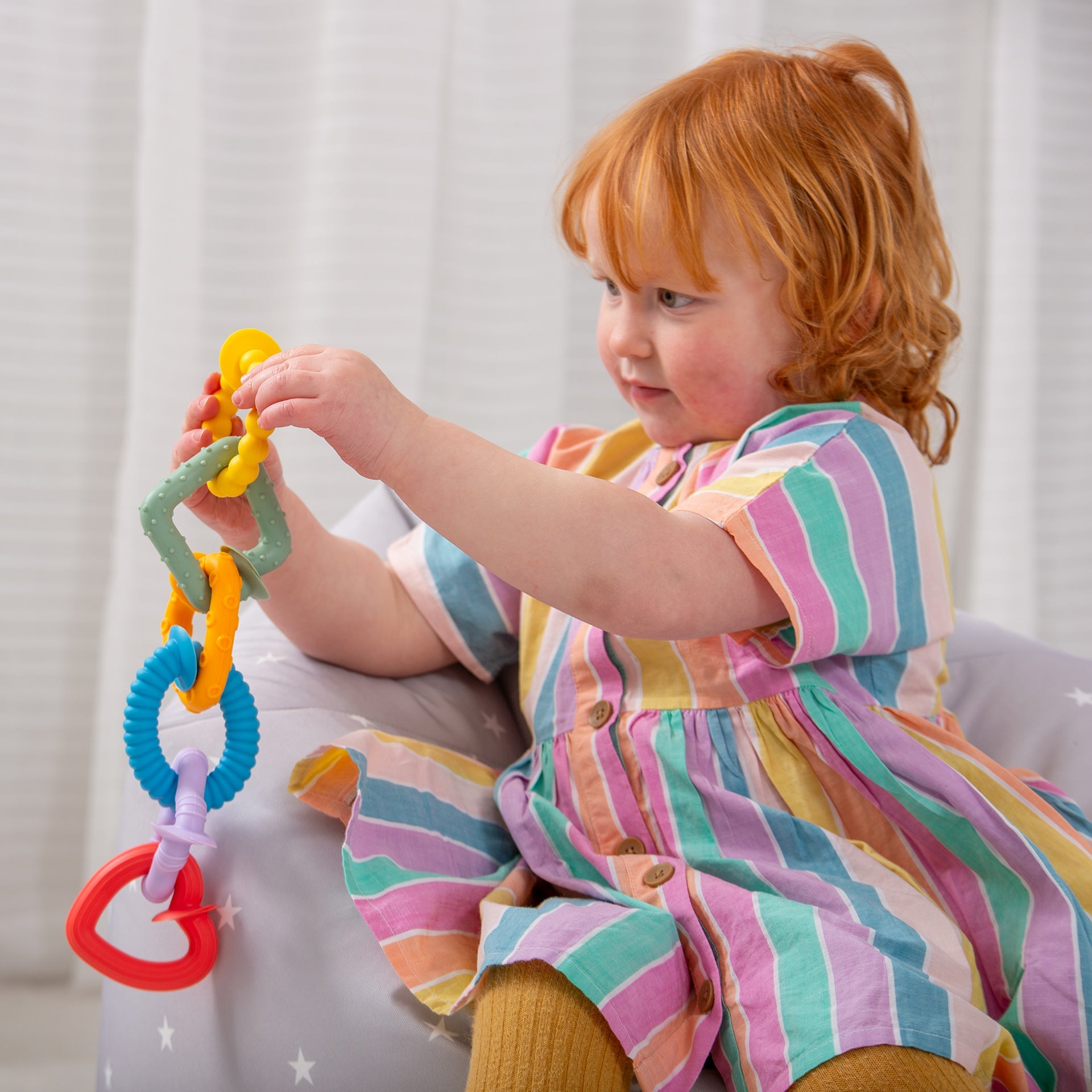 Toddler playing with colorful baby teething rings and sensory toy set