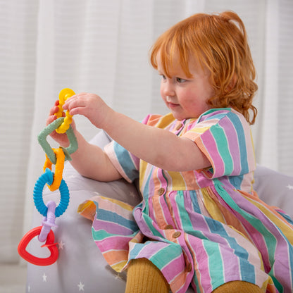 Toddler playing with colorful baby teething rings and sensory toy set