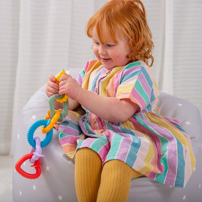 Toddler playing with colorful sensory teething toy on star-patterned bean bag