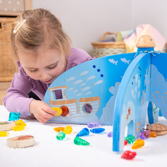 Child playing with wooden ocean-themed toy set featuring colorful sea creatures and a boat, ideal for imaginative play.