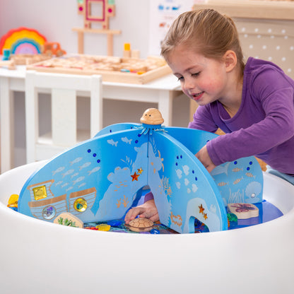 Child playing with wooden ocean-themed sensory water table featuring sea creatures and underwater scenes