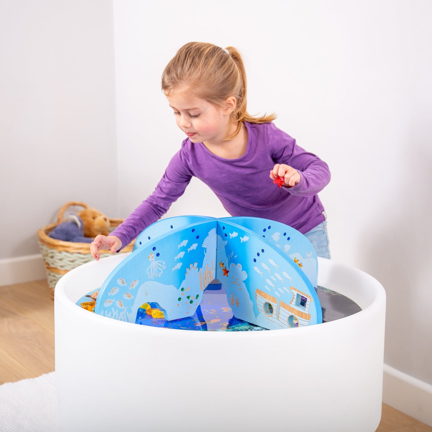 Child playing with ocean-themed water table toy featuring sea creatures and submarine