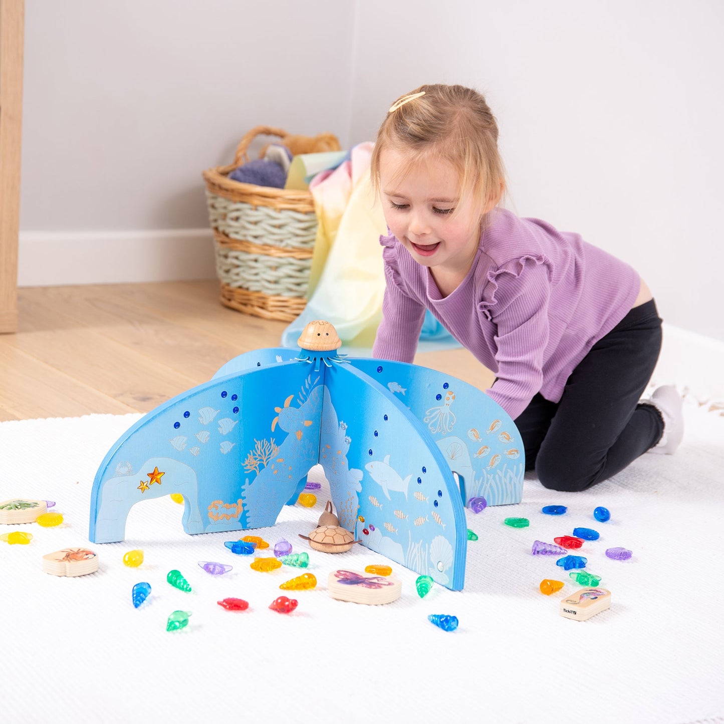Child playing with wooden ocean-themed toy set featuring sea creatures and colorful acrylic gems