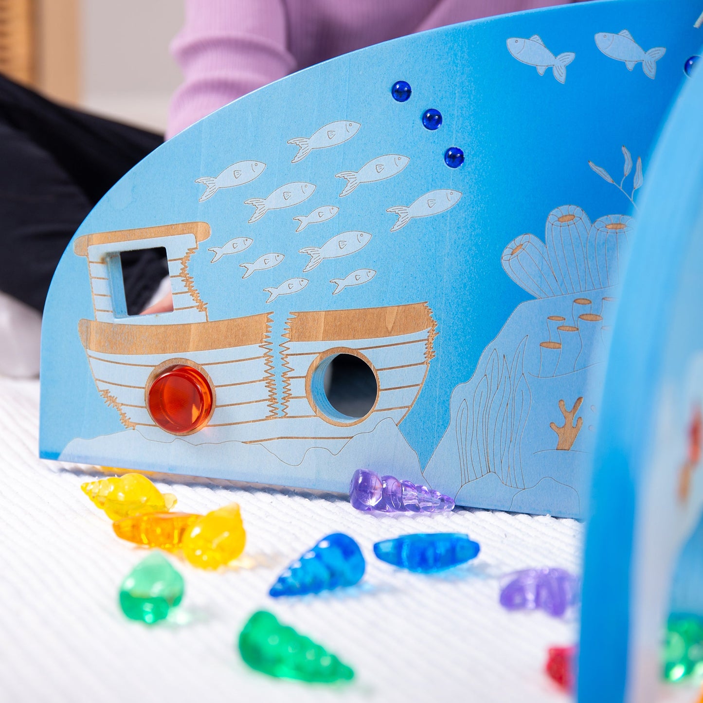 Underwater-themed wooden toy with boat, fish, and colorful acrylic sea creatures for sensory play